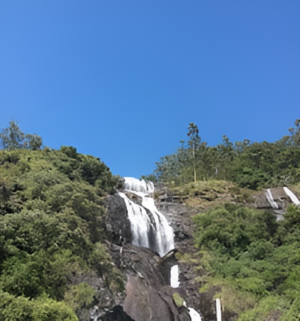 Lush green hills surrounding Power House Waterfalls Kerala